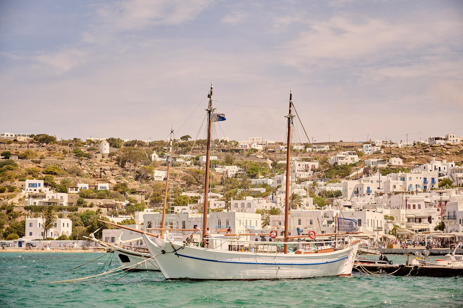 Scenic view of moored boats and whitewashed houses on Mykonos island shore.