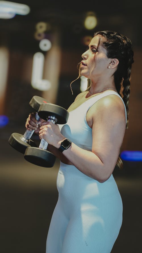 A woman in a white top lifting weights