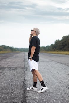 A stylish man stands confidently on a rural road in Breves, Brazil, wearing modern casual attire.