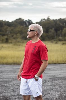 A man with sunglasses and short hair poses in a red t-shirt on a rural road in Breves, Brazil.