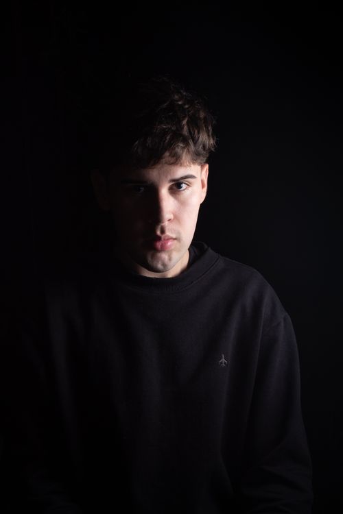Free Dramatic portrait of a young man with short hair against a black background. Stock Photo