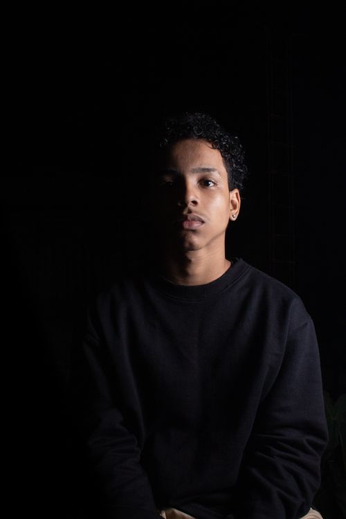 Free Striking portrait of a young man in black attire against a dark background, showcasing dramatic lighting. Stock Photo