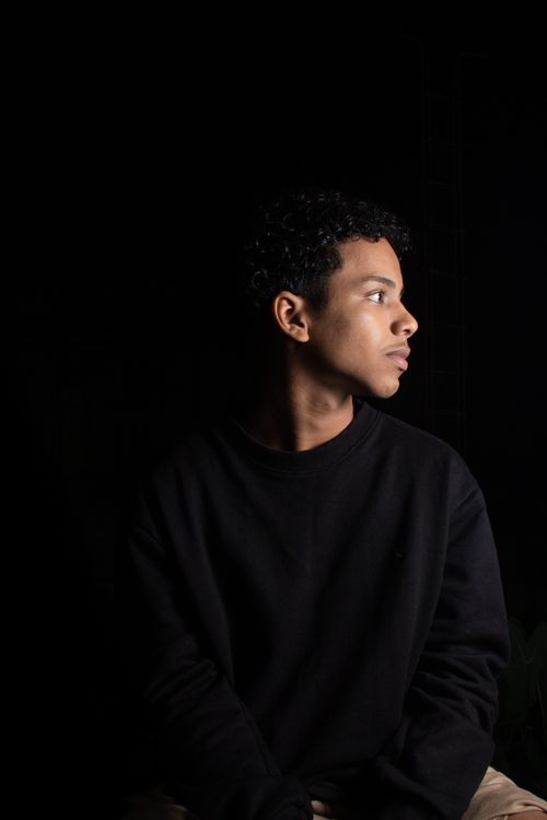 Free Dramatic studio portrait of a young man against a black background, conveying a moody and thoughtful mood. Stock Photo