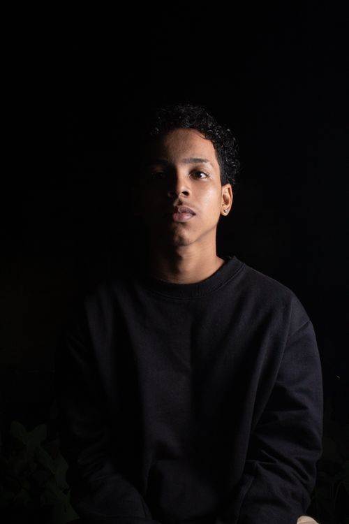 Free Atmospheric studio portrait of a young man in a black pullover against a dark background. Stock Photo