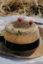 A straw hat with flowers on it sitting on top of a blanket