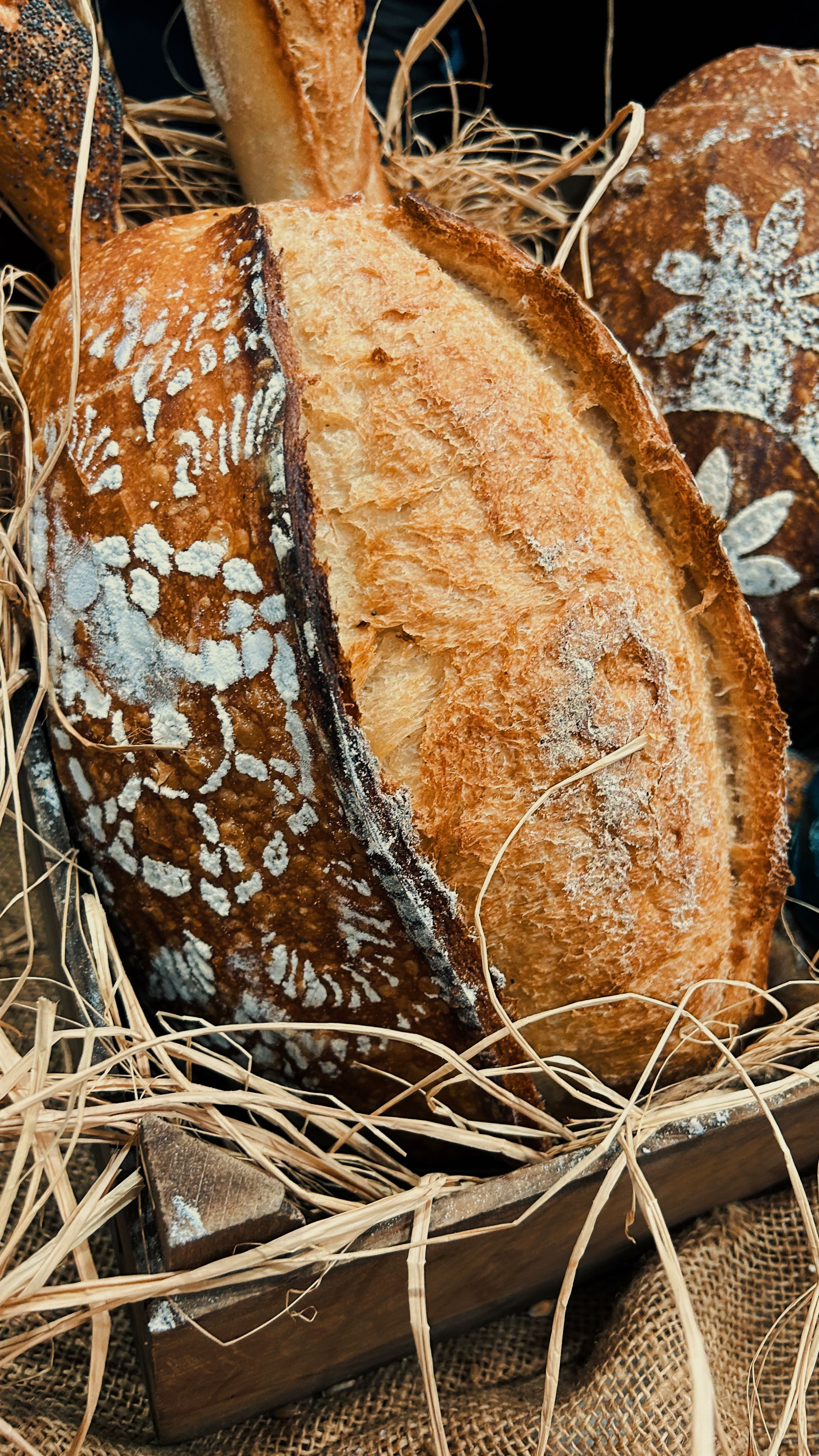 Close-up of artisan bread with decorative crust pattern, in rustic setting.