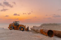 Large pipes laid out on a beach construction site during a beautiful sunset, ready for installation.  Large pipes laid out on a beach construction site during sunset.