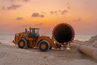 Large pipes laid out on a beach construction site during a beautiful sunset, ready for installation.  Large pipes laid out on a beach construction site during sunset.