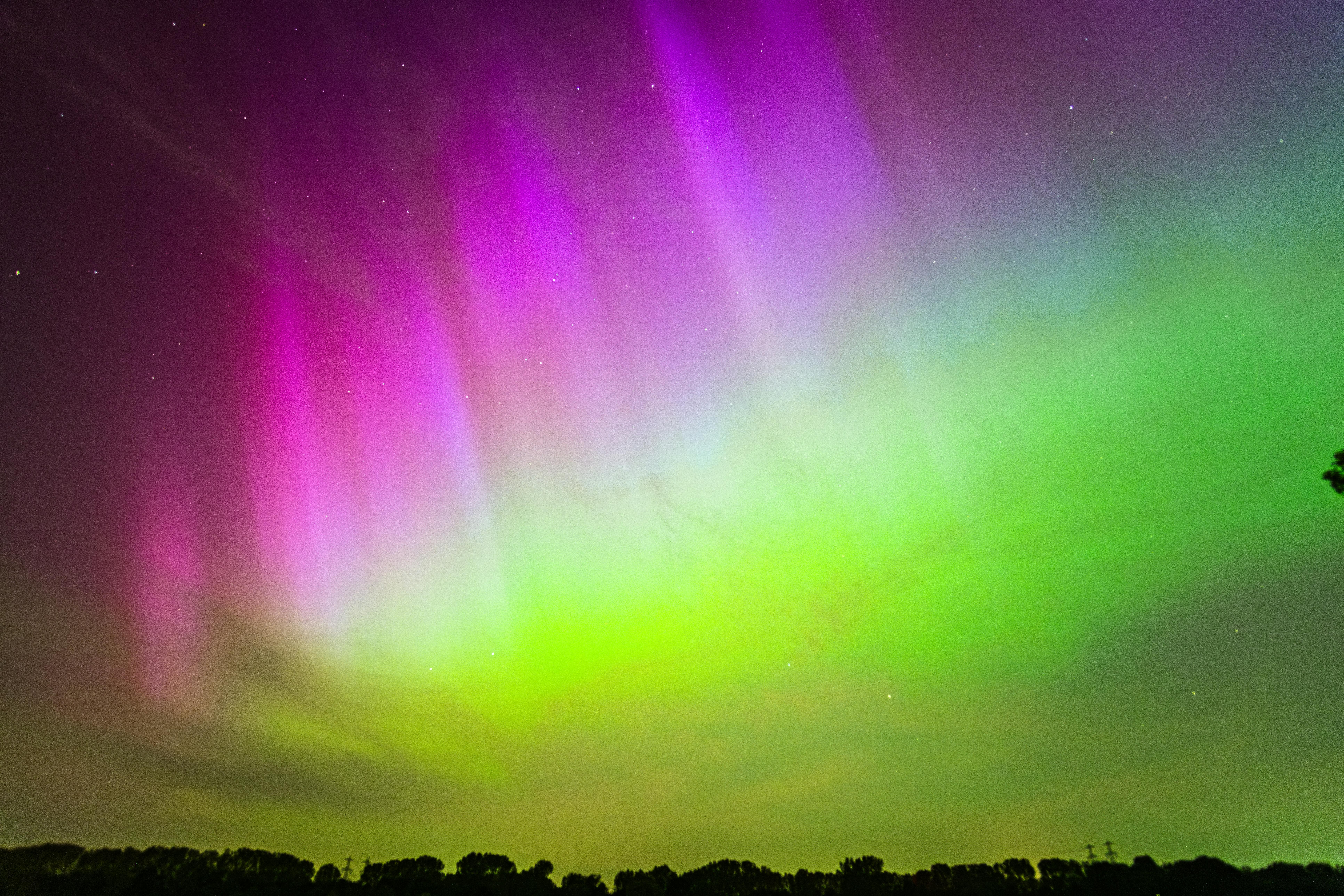 Colorful aurora borealis display over Roermond, Netherlands; vibrant night sky scene.