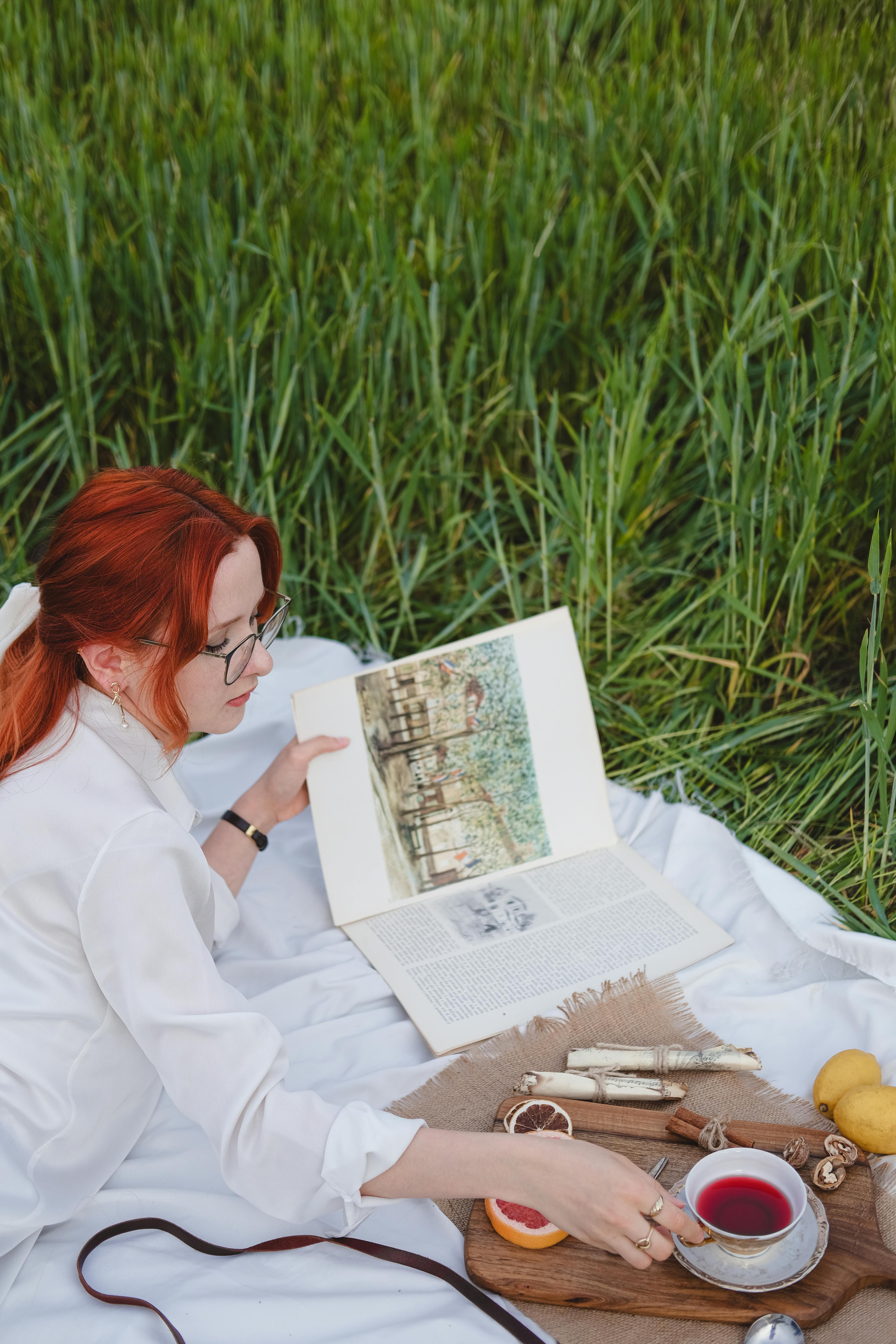 Woman in White Shirt Lying Down with Book and Tea on Picnic · Free