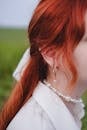 A woman with red hair and pearl earrings