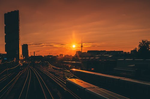 A sunset over a train track with buildings in the background