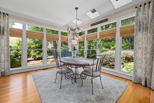 Bright dining area with floor-to-ceiling windows overlooking a garden, featuring modern furniture and elegant decor.
