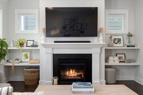 A white fireplace with a tv above it