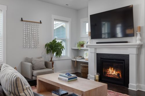 Free A stylish and cozy living room featuring a fireplace, armchair, and wall-mounted TV for a comfortable atmosphere. Stock Photo