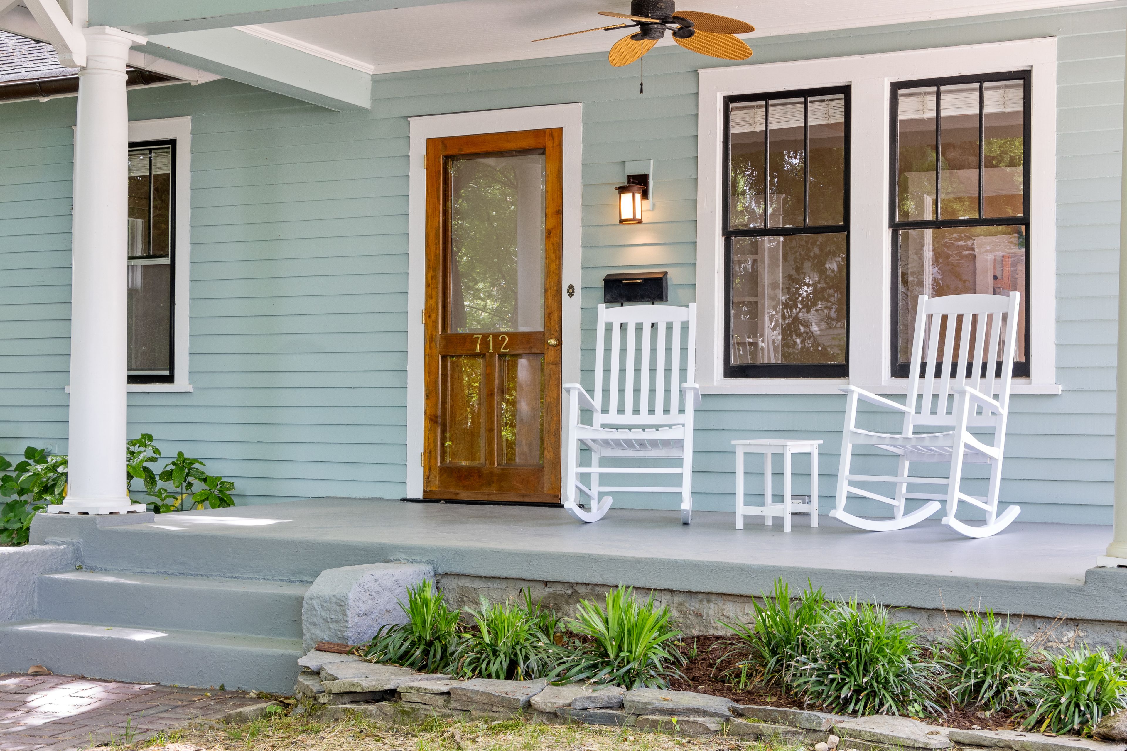A front porch with white rocking chairs