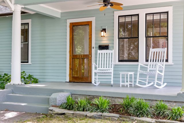 Covered front porch with rocking chairs and a wooden entry door — photo by Curtis Adams on Pexels