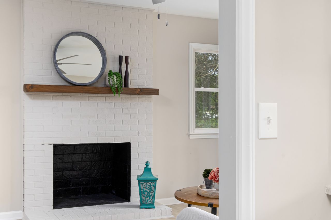 White painted brick fireplace with wood mantel shelf and round mirror
