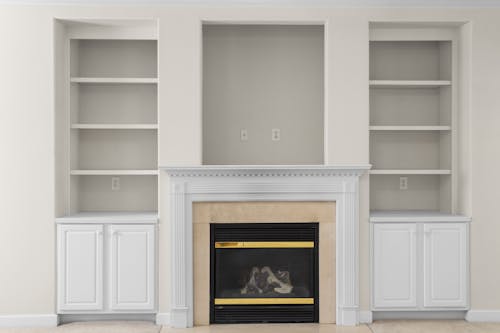 A fireplace with white cabinets and shelves