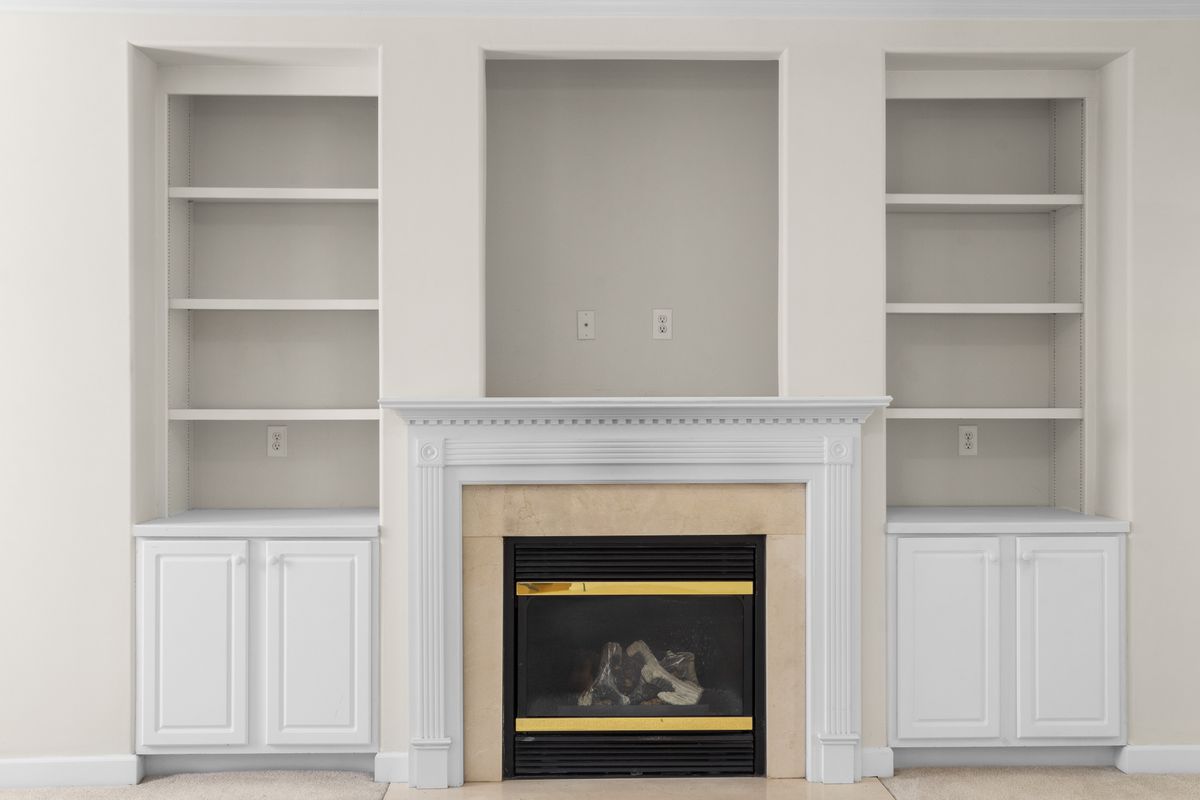 Alcove shelves either side of a chimney breast painted the same colour as the wall and styled with books and plants
