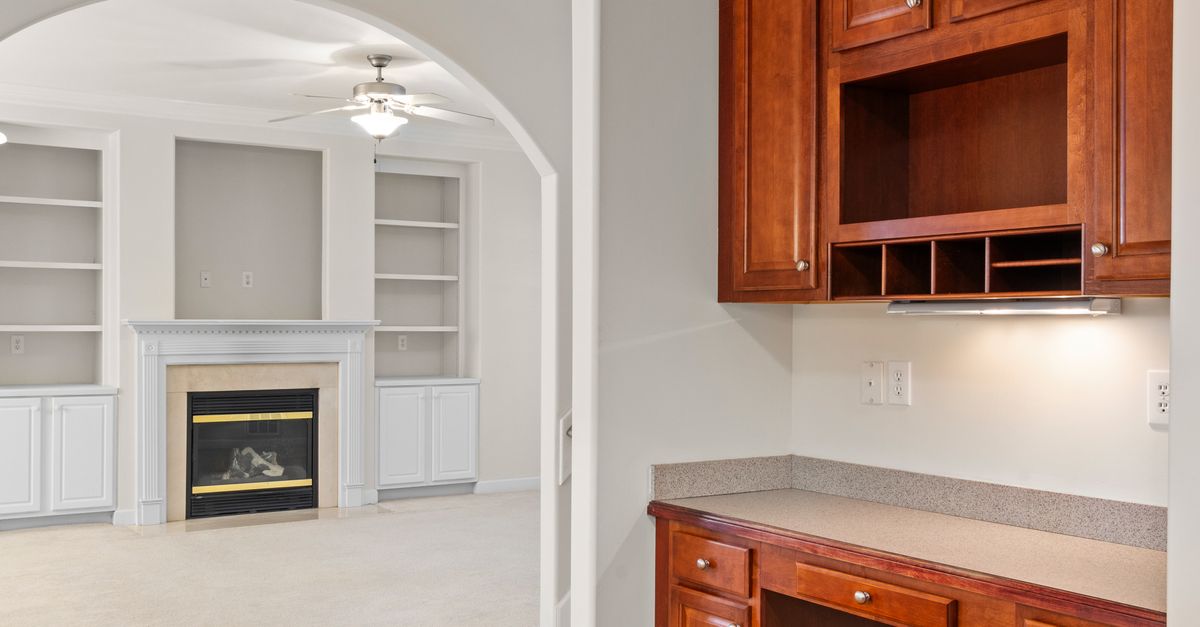 Spacious, well-lit room featuring a fireplace, wooden cabinets, clean interiors, and open shelves.