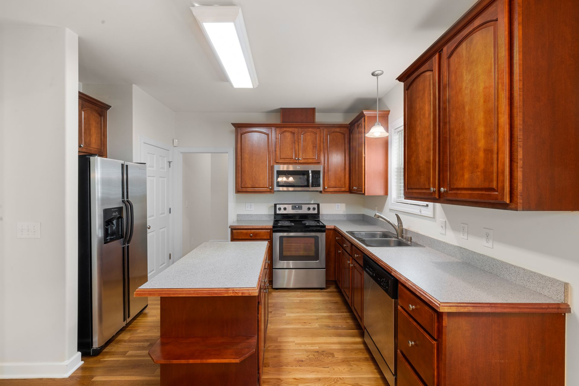 Spacious kitchen with wooden cabinets, island, and stainless steel appliances, ideal for modern homes.