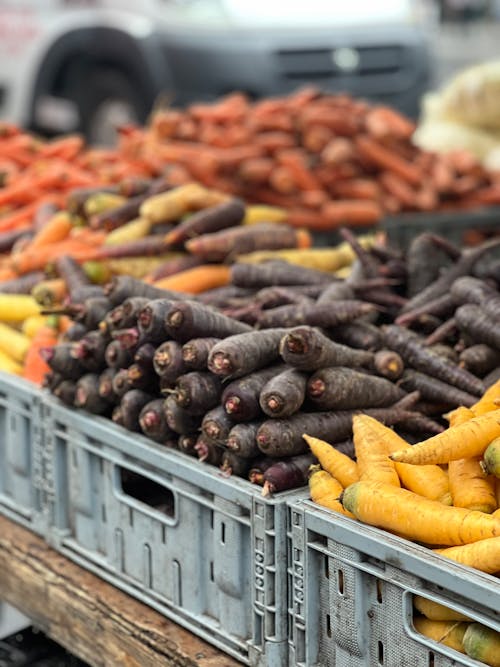 Carrots and other vegetables are in crates at a market