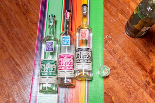 Vibrant bottles of Mezcal on a colorful tablecloth in CDMX, Mexico, showcasing traditional Mexican spirits.