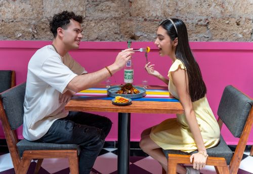 Free A happy couple sharing food at a vibrant restaurant in Mexico City, enjoying a romantic moment. Stock Photo