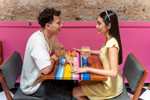 Free A young couple enjoying drinks at a lively restaurant with colorful decor in CDMX, Mexico. Stock Photo