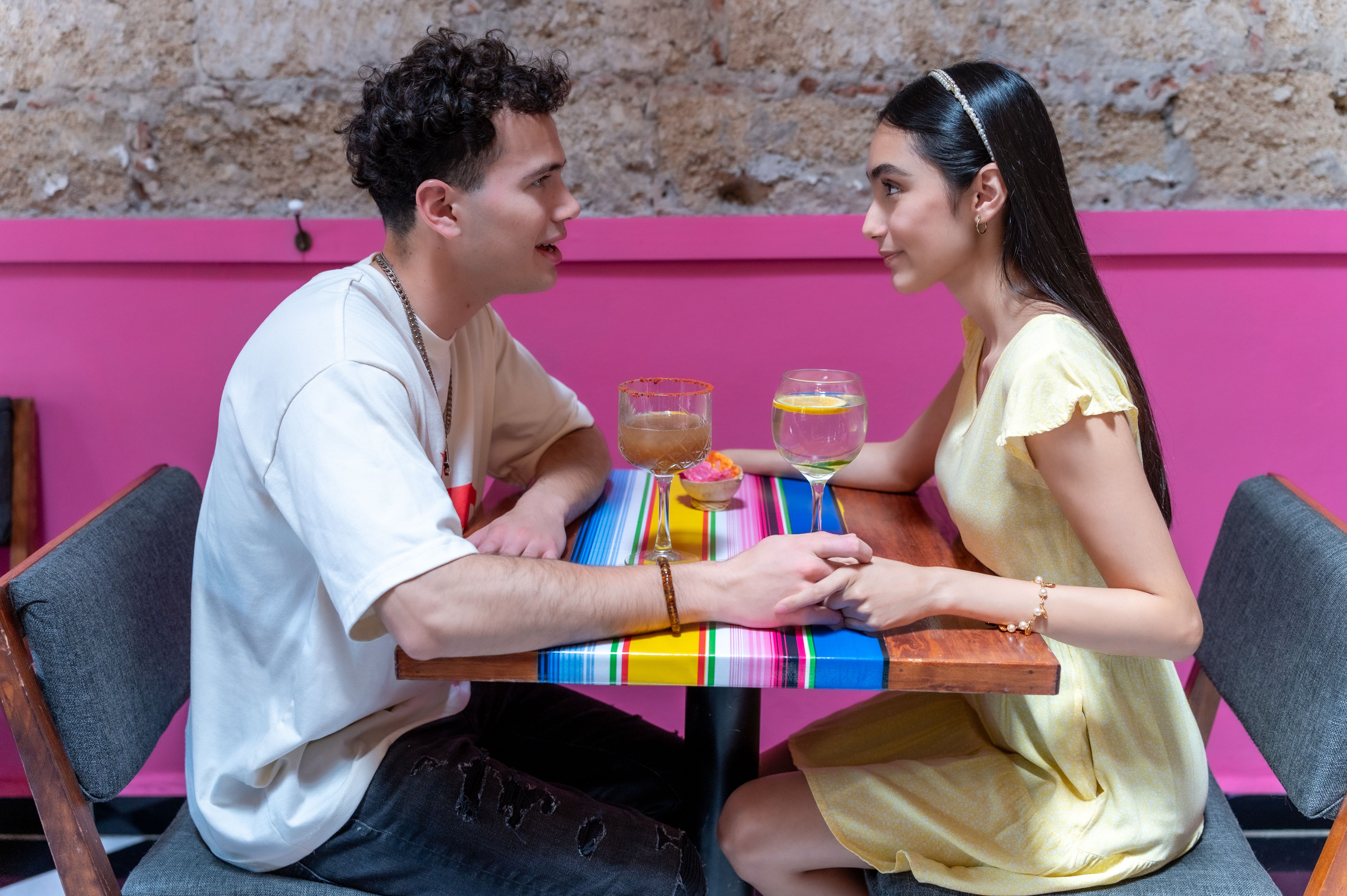 Young couple holding hands while enjoying drinks at a vibrant CDMX restaurant.