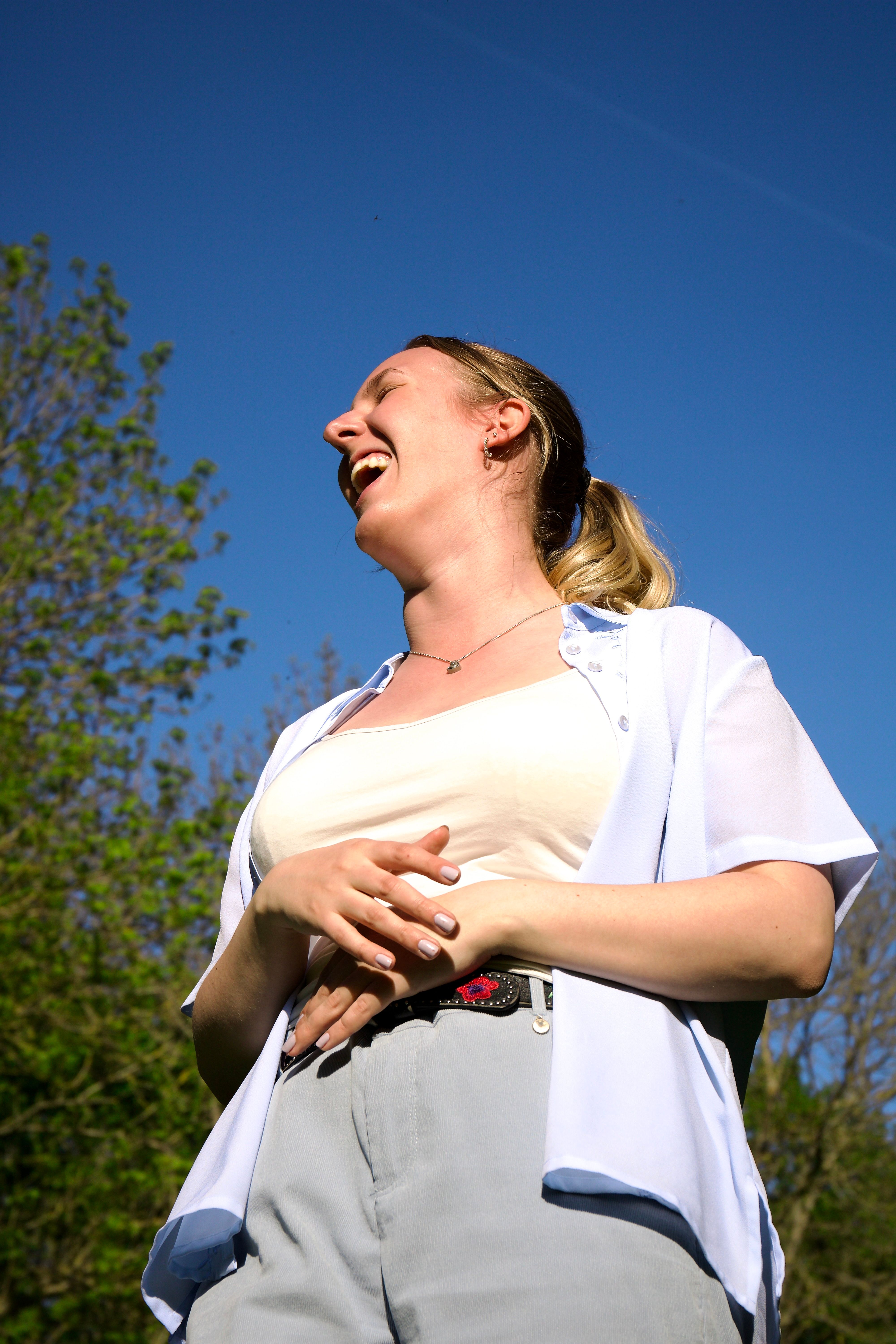 Smiling woman enjoying a sunny day outdoors, expressing joy and happiness.
