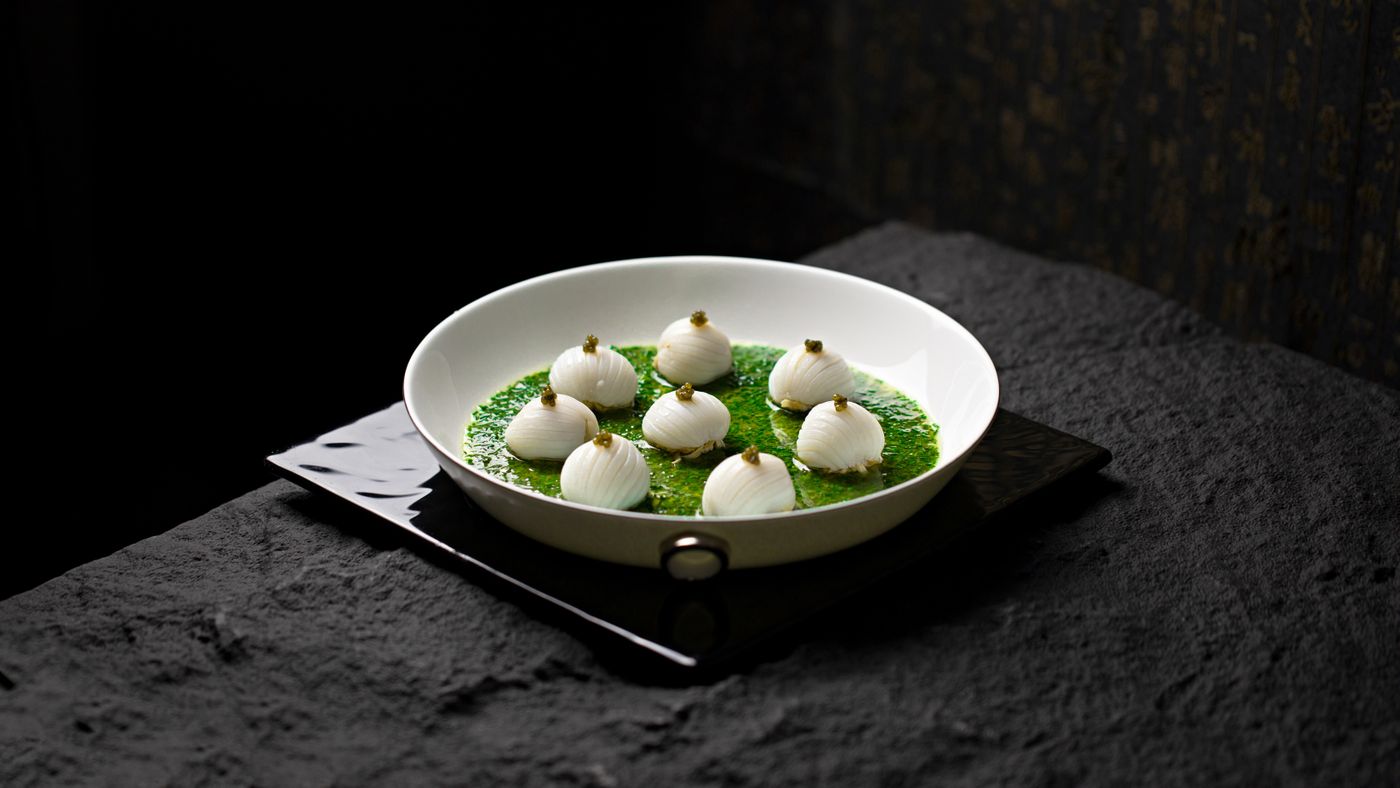 Cipolline su salsa verde in un piatto bianco
