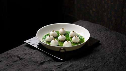 Free Artistic presentation of onions in herb sauce on a white plate against dark background Stock Photo