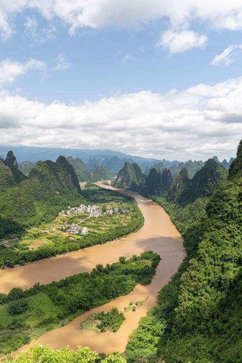 Free Breathtaking aerial view of Li River meandering through lush karst mountains under a partly cloudy sky in Guilin, China. Stock Photo