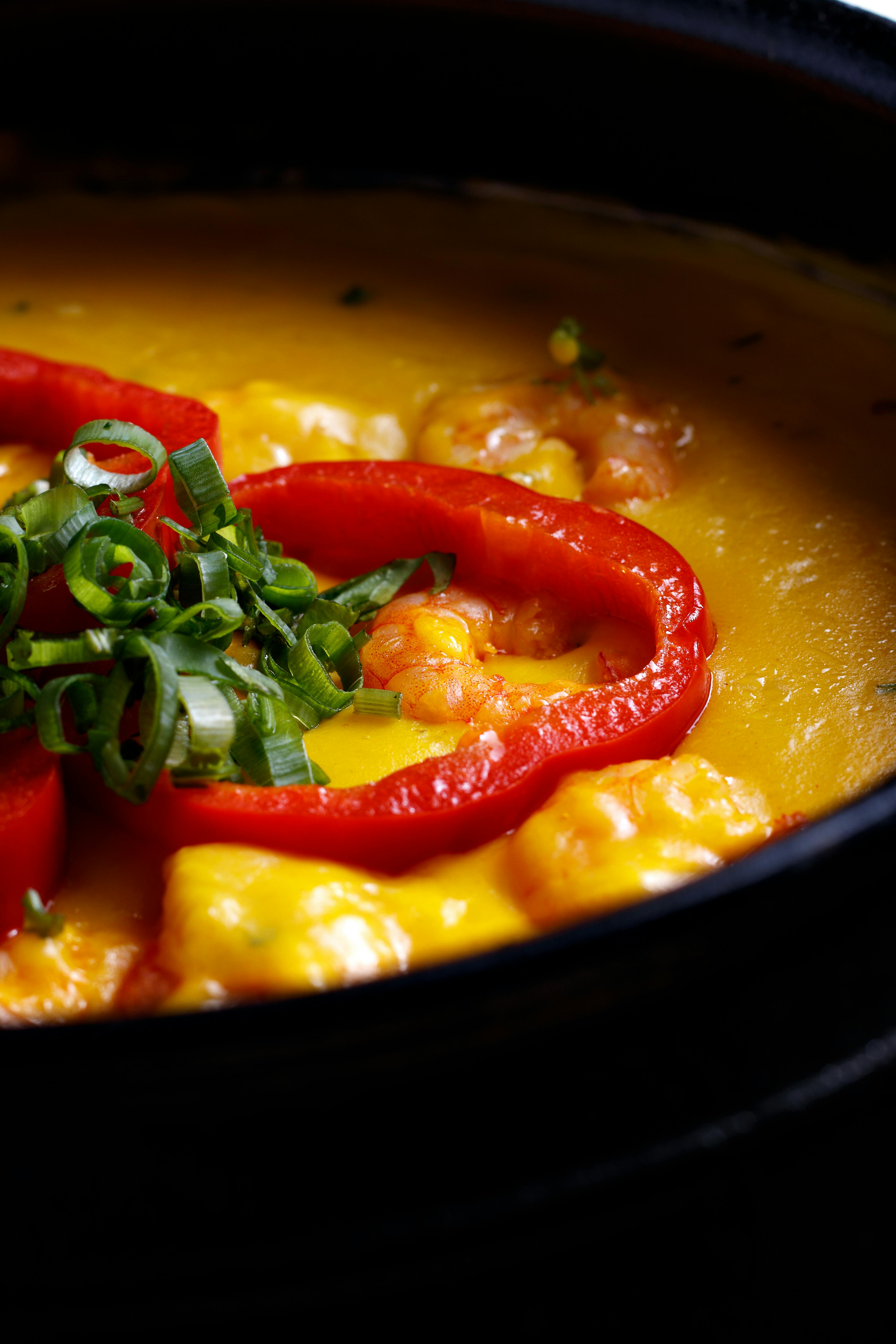 Traditional Brazilian moqueca seafood stew in a clay pot with shrimp, coconut milk, and malagueta peppers