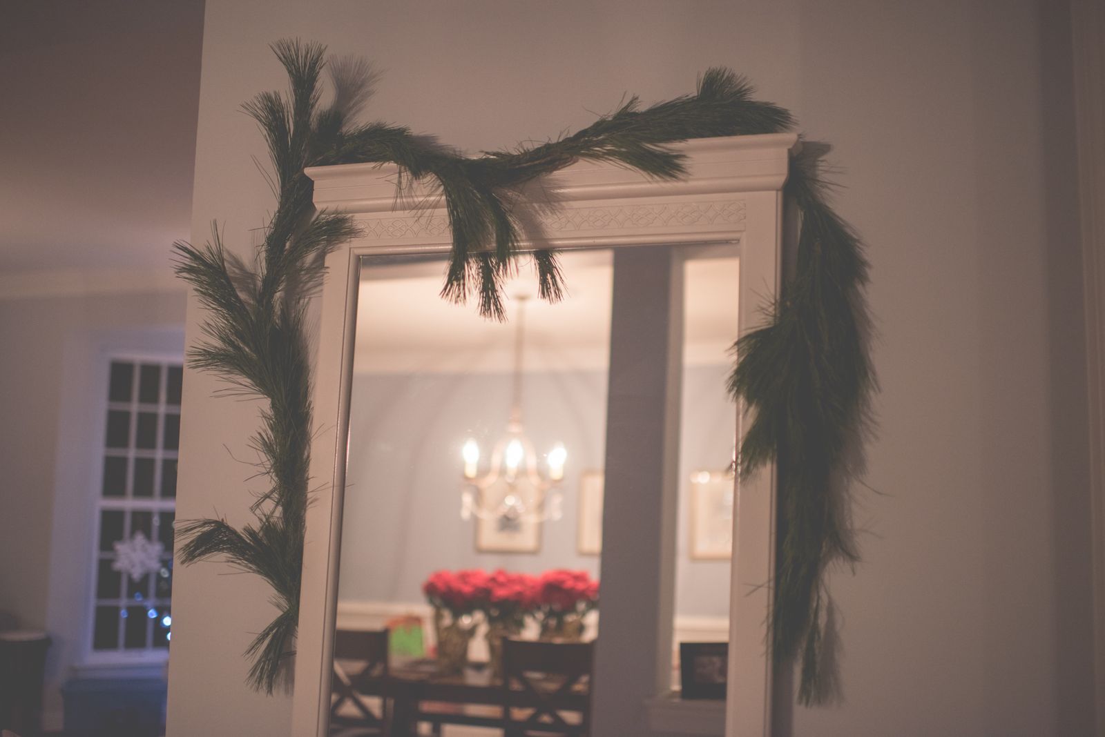 mirror adorned with festive green garland, warm dining setting, landscape