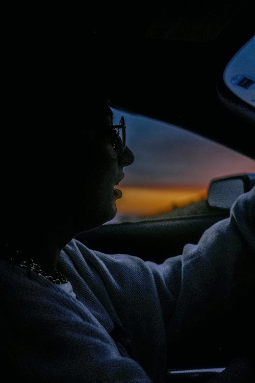A woman is driving at sunset