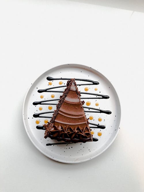 A piece of chocolate cake on a plate with drizzles