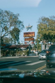 Vintage street scene of Astro Burgers on Santa Monica Blvd, Los Angeles with cars and trees.