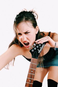 Energetic woman passionately playing electric guitar during studio shoot.