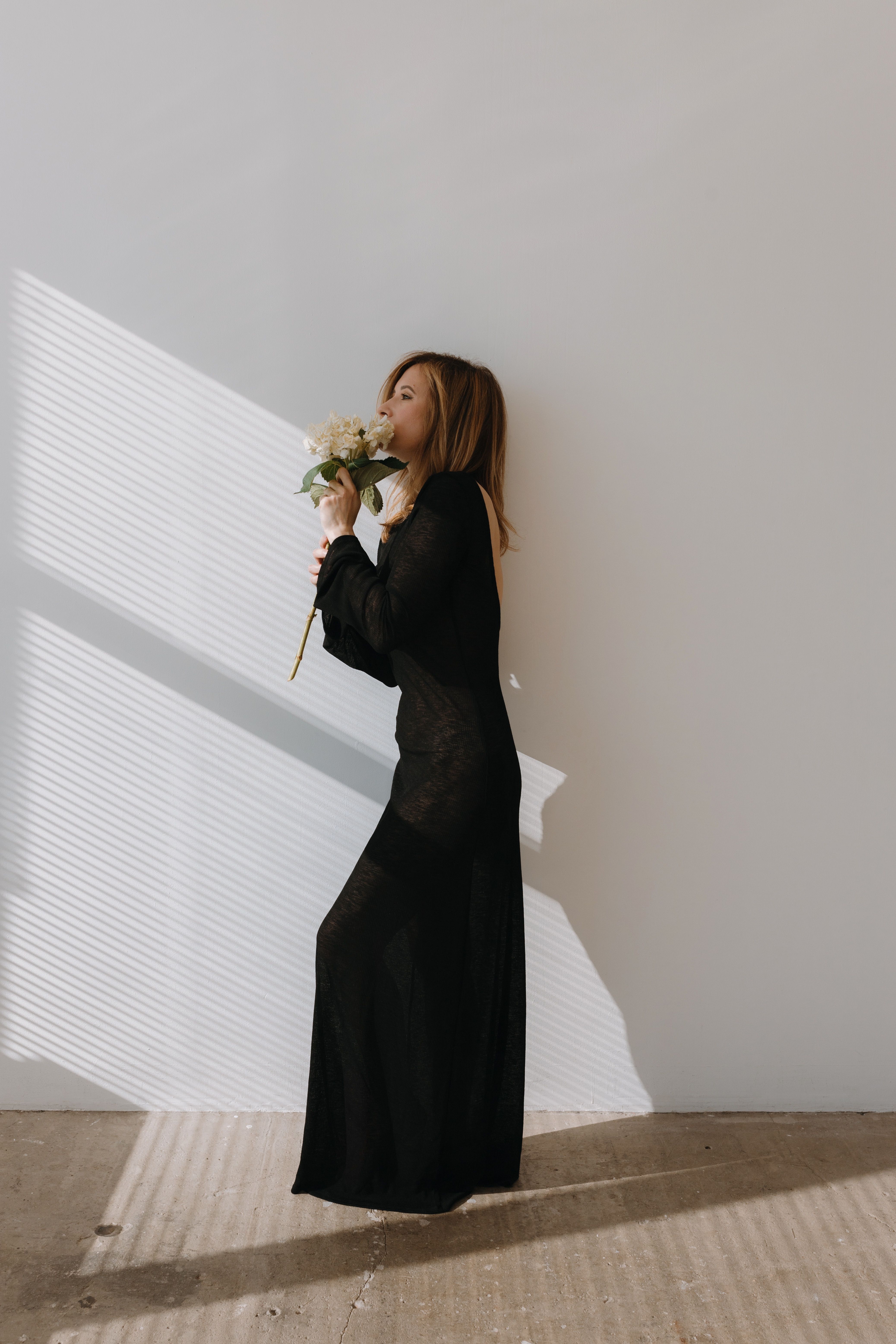 Photo of a Young Woman in a Black Dress Holding White Flowers · Free ...