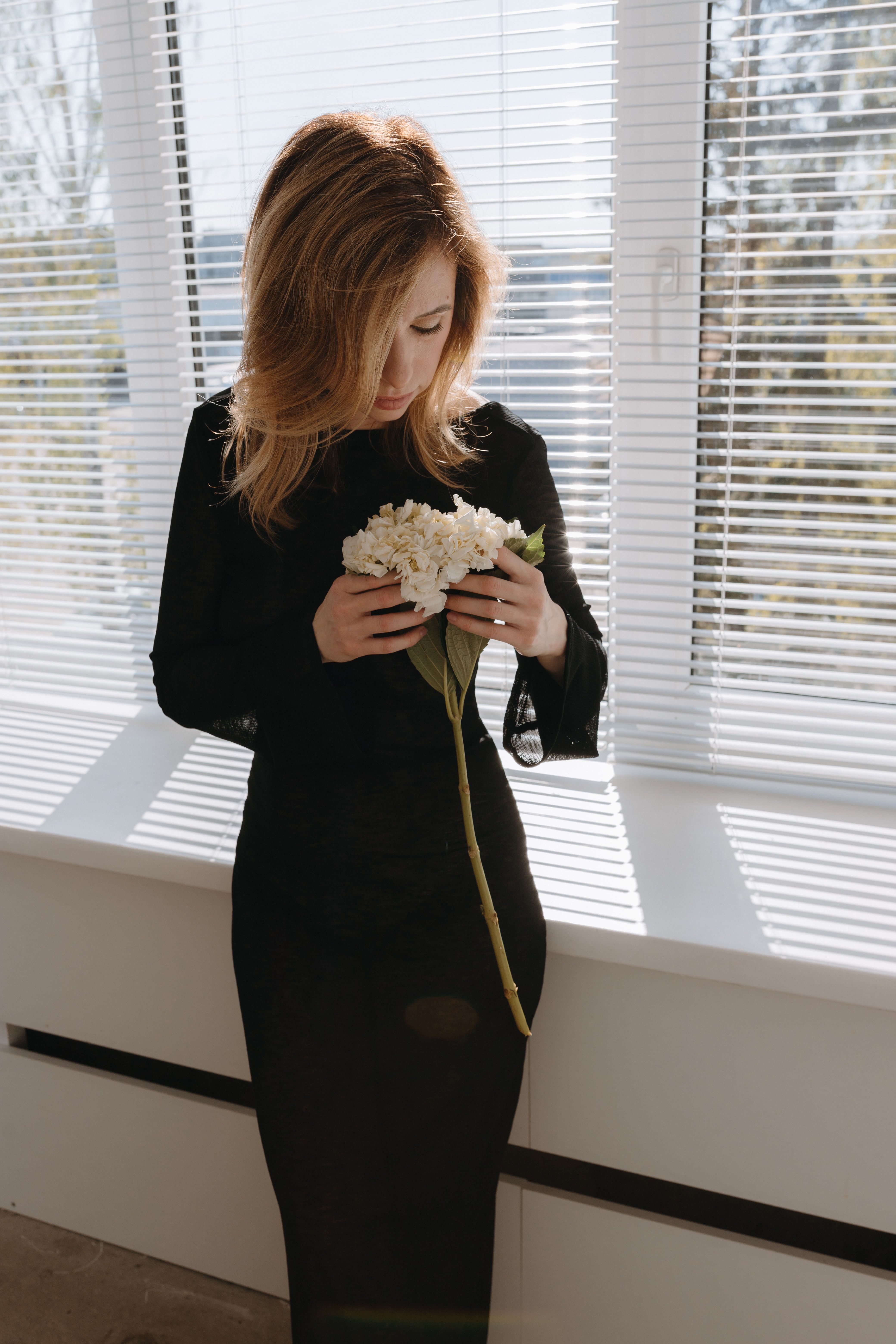 Photo of a Young Woman in a Black Dress Holding White Flowers · Free ...