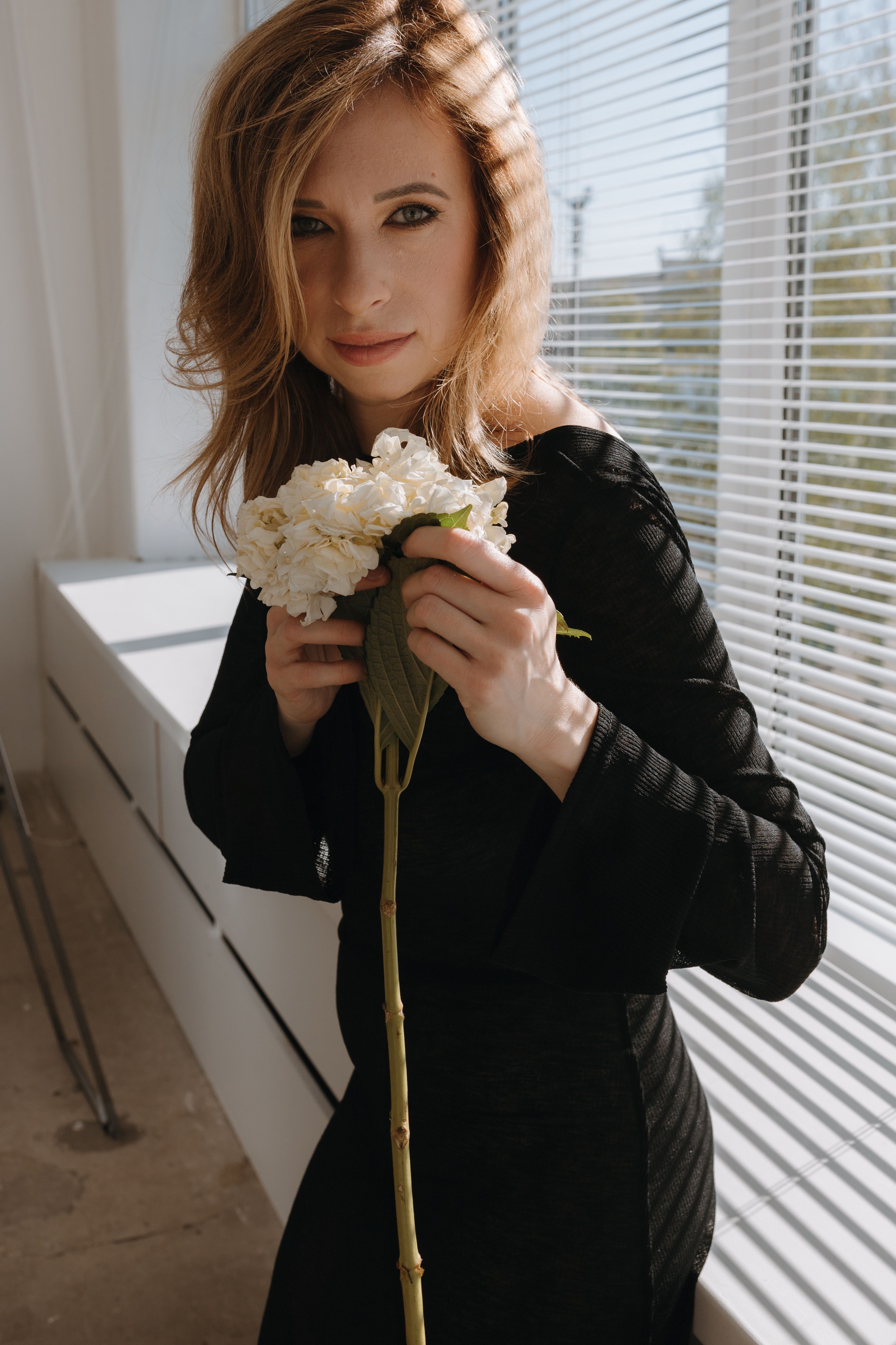 Photo of a Young Woman in a Black Dress Holding White Flowers · Free ...