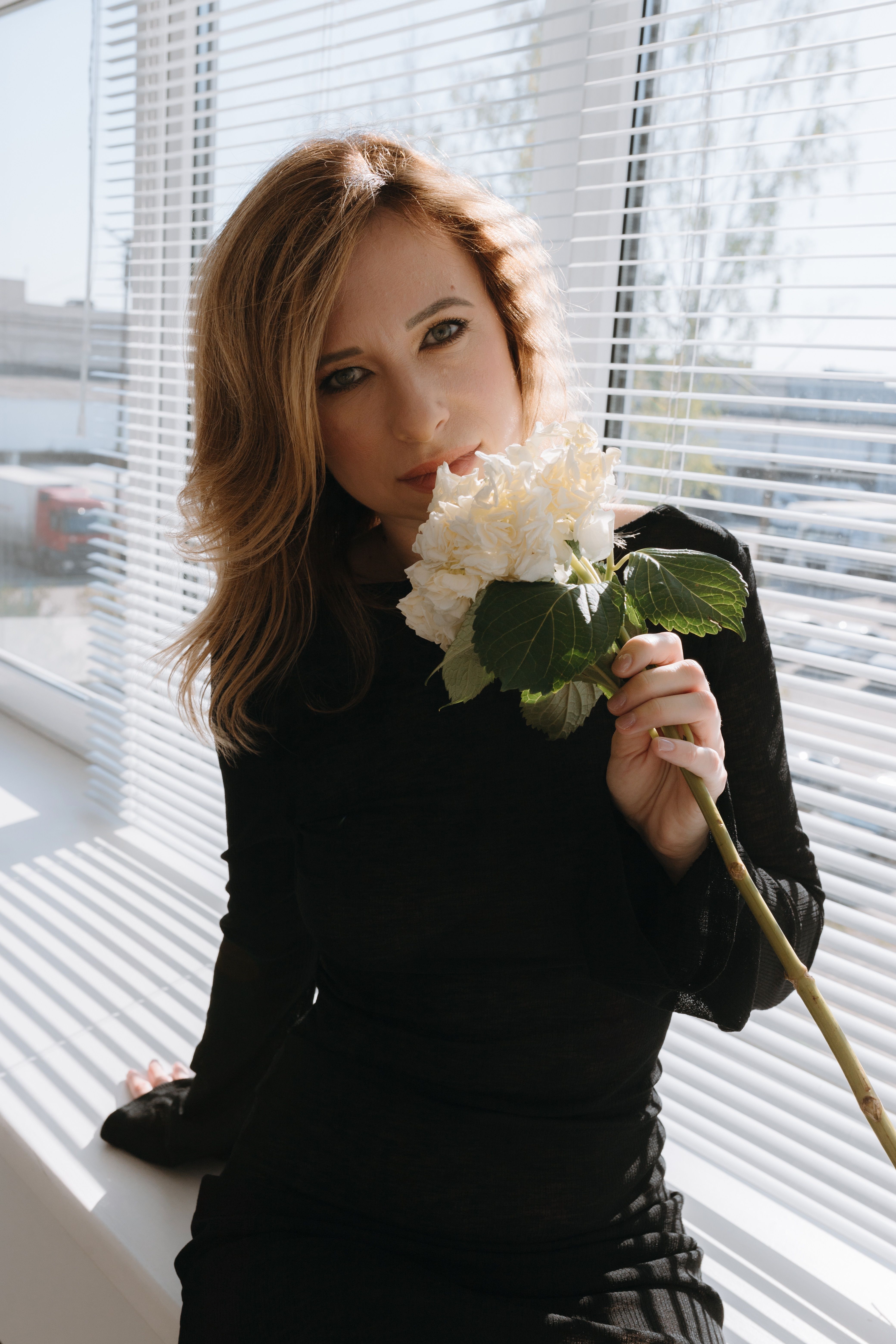 Photo of a Young Woman in a Black Dress Holding White Flowers · Free ...