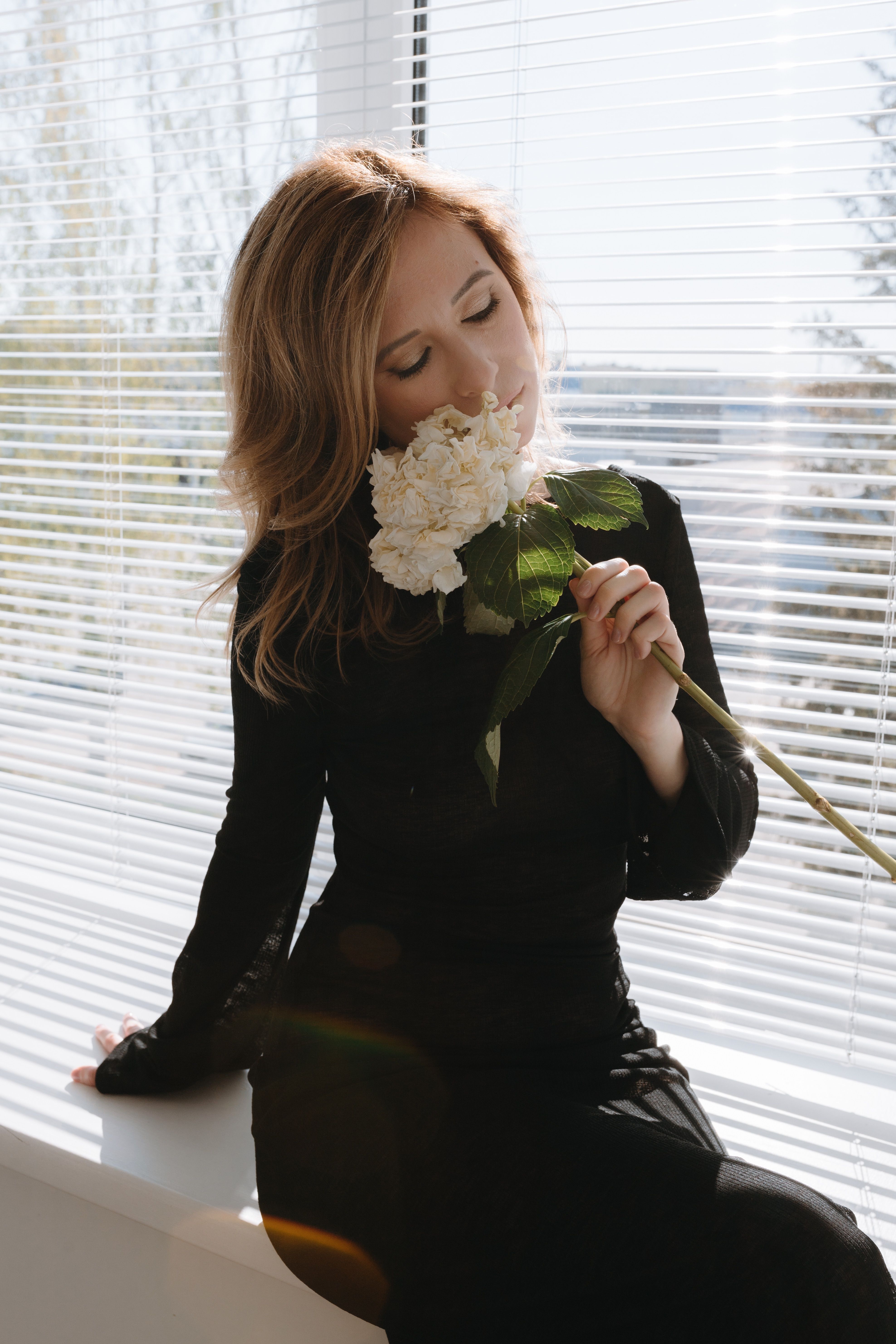 Photo of a Young Woman in a Black Dress Holding White Flowers · Free ...