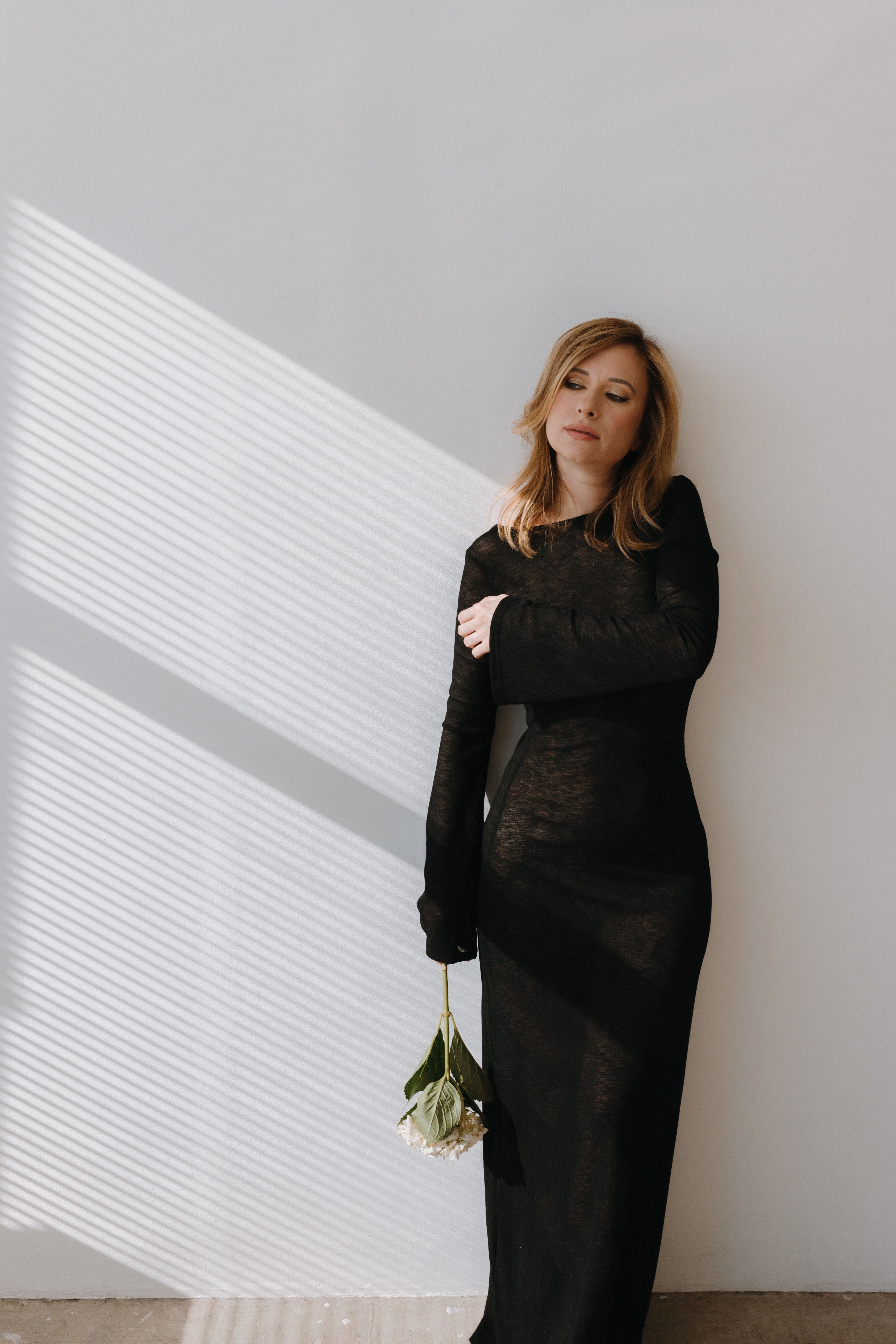 Photo of a Young Woman in a Black Dress Holding Flowers · Free Stock Photo