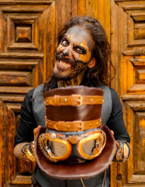 Free Smiling man with painted face in a Day of the Dead costume holding a unique hat in Mexico City. Stock Photo