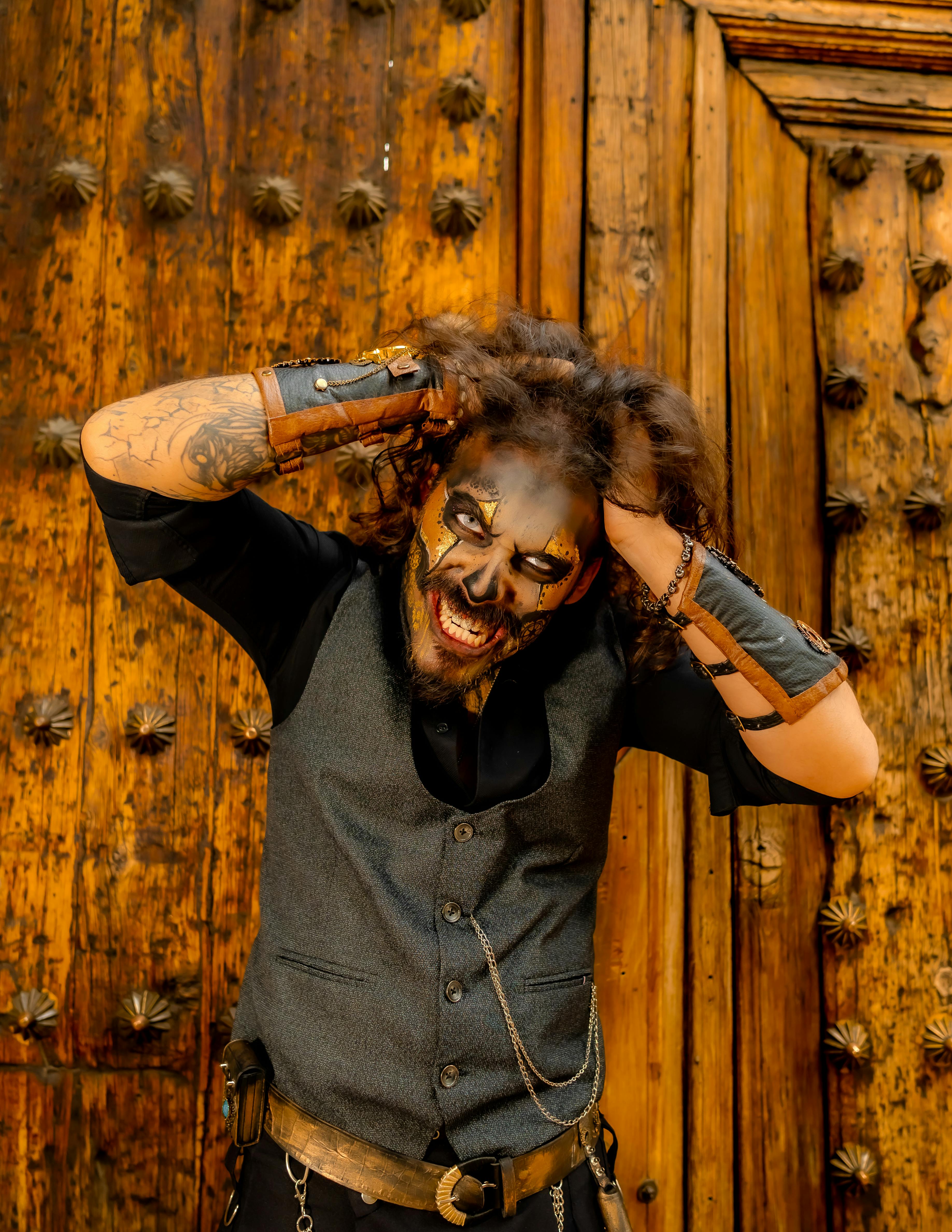 A creatively painted man in a costume striking a dynamic pose with a wooden background.