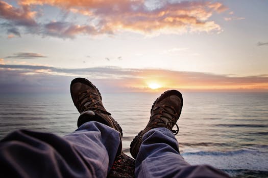 脚踩远足靴，站在昆士兰州伯利头的悬崖上，俯瞰着海洋日落